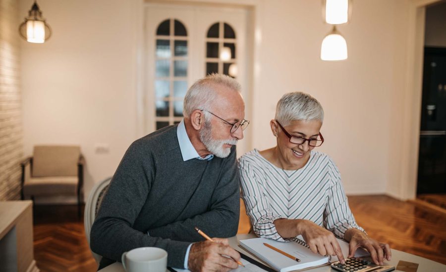 A happy senior couple calculating their finances in a beautiful home. Wohnrecht Österreich